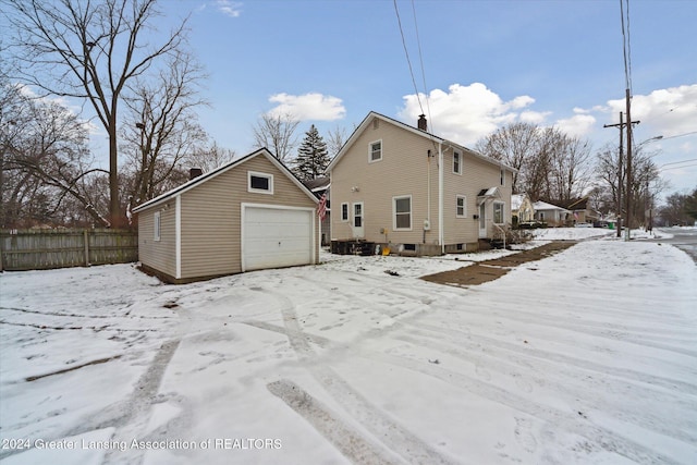 snow covered property featuring a garage and an outdoor structure