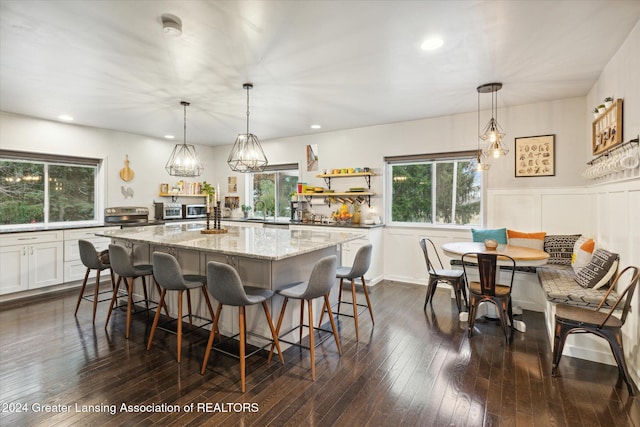 kitchen featuring dark hardwood / wood-style floors, a center island, white cabinetry, and hanging light fixtures