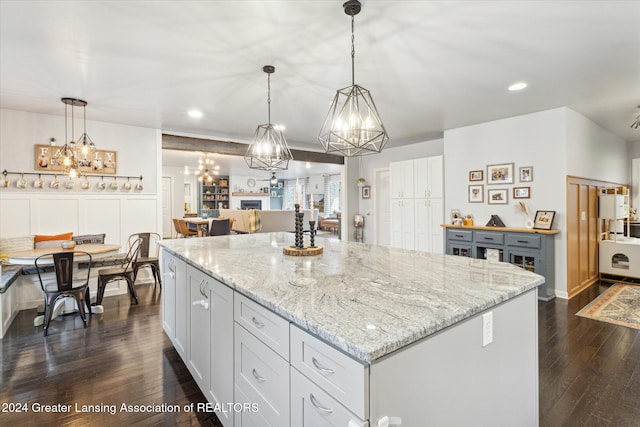 kitchen featuring pendant lighting, dark hardwood / wood-style floors, a kitchen island, and light stone counters