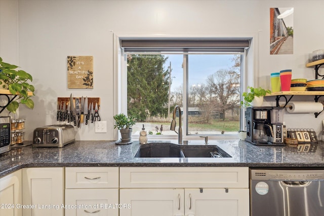 kitchen featuring white cabinetry, stainless steel dishwasher, dark stone counters, and sink