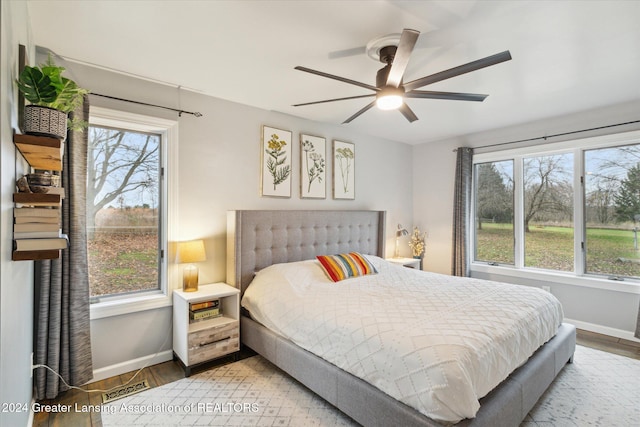 bedroom with hardwood / wood-style flooring, ceiling fan, and multiple windows