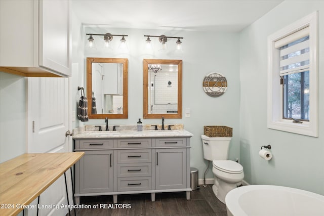 bathroom with a tub, vanity, wood-type flooring, and toilet