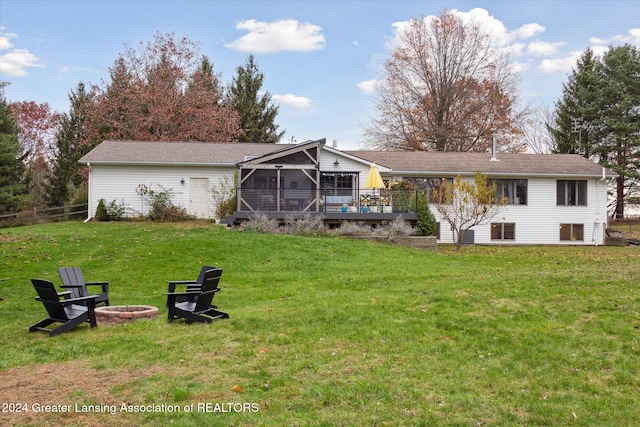 rear view of house featuring a fire pit, a sunroom, a yard, and a wooden deck