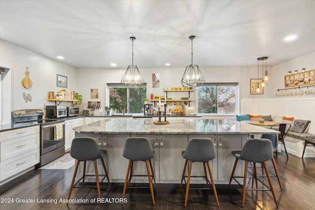 kitchen with a kitchen bar, white cabinetry, stainless steel electric range oven, and dark wood-type flooring