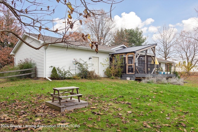 rear view of property featuring a sunroom and a yard