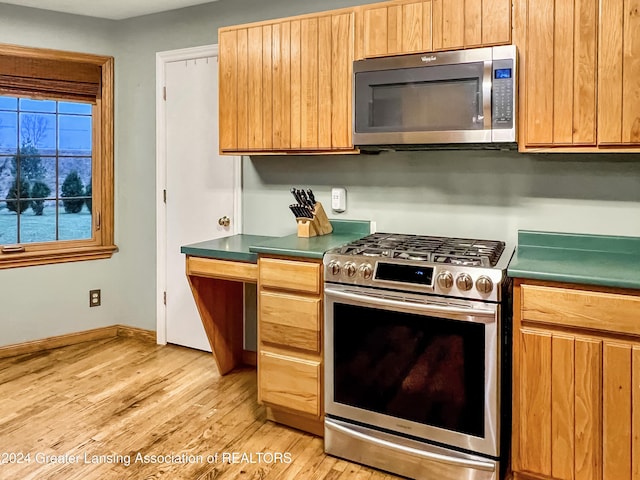 kitchen with appliances with stainless steel finishes and light hardwood / wood-style flooring