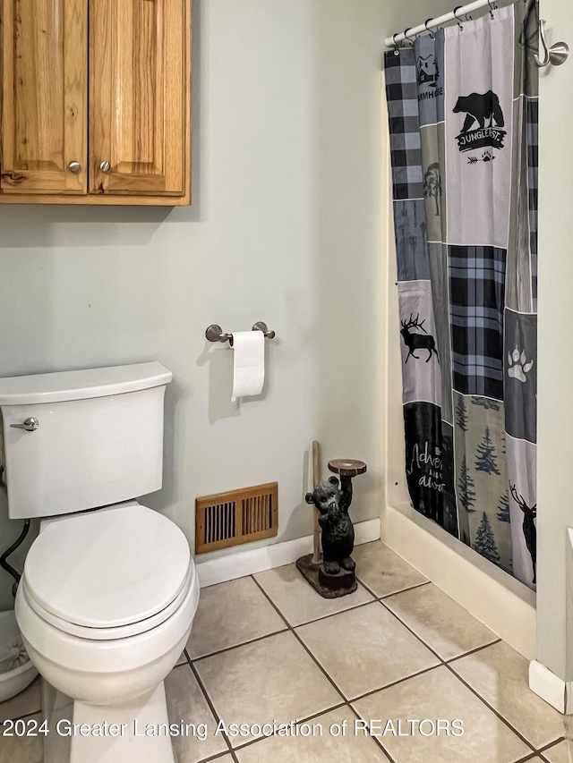 bathroom featuring tile patterned floors, toilet, and walk in shower