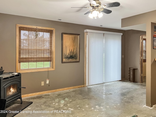 interior space with a wood stove and ceiling fan