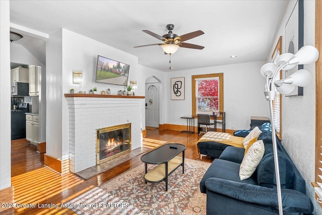 living room with ceiling fan, a fireplace, and light wood-type flooring