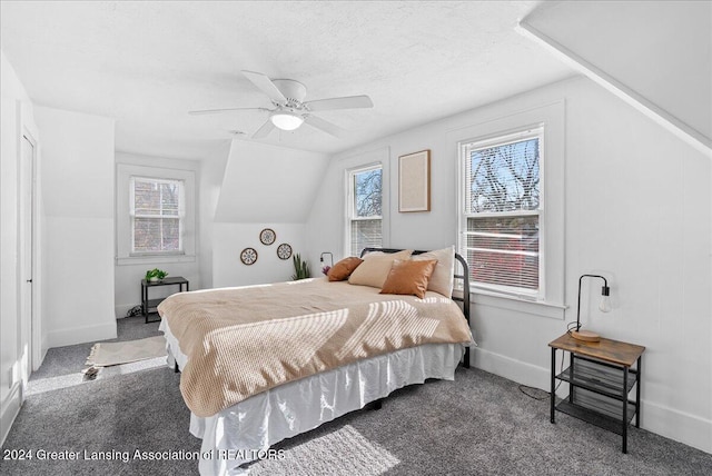 carpeted bedroom with multiple windows, ceiling fan, and vaulted ceiling