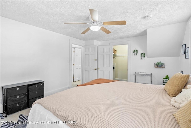 bedroom featuring a textured ceiling, light colored carpet, ceiling fan, a spacious closet, and a closet