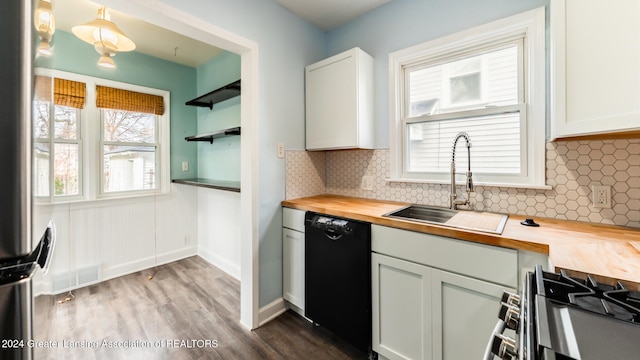 kitchen with wood counters, stainless steel appliances, sink, pendant lighting, and white cabinetry