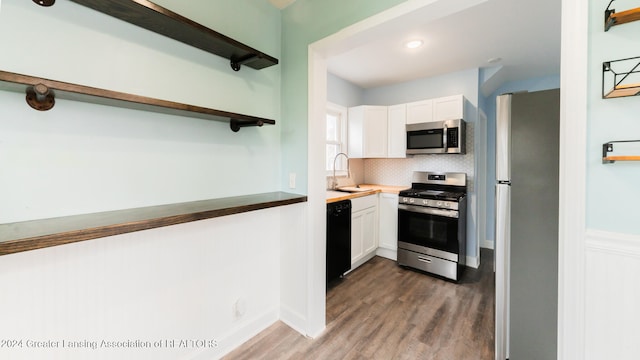 kitchen with white cabinets, sink, dark hardwood / wood-style floors, decorative backsplash, and stainless steel appliances