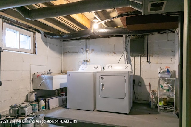 washroom featuring washing machine and dryer, sink, and electric panel