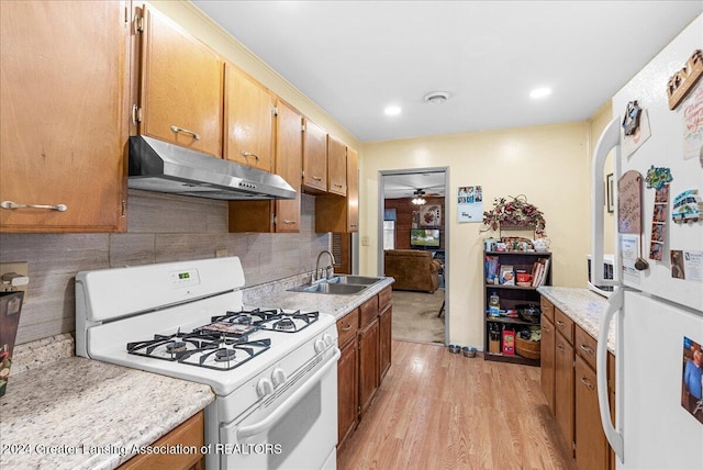 kitchen featuring decorative backsplash, light wood-type flooring, white appliances, ceiling fan, and sink