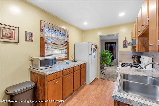 kitchen featuring white appliances, light hardwood / wood-style floors, ornamental molding, and sink