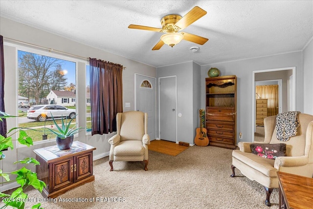 sitting room with ceiling fan, light colored carpet, and a textured ceiling