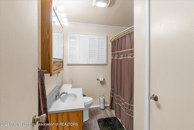 bathroom featuring walk in shower, crown molding, wood-type flooring, toilet, and vanity