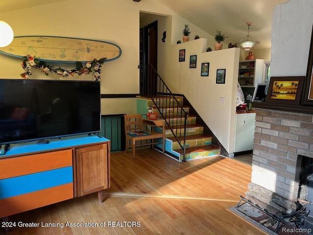 stairway with wood-type flooring, a brick fireplace, and lofted ceiling