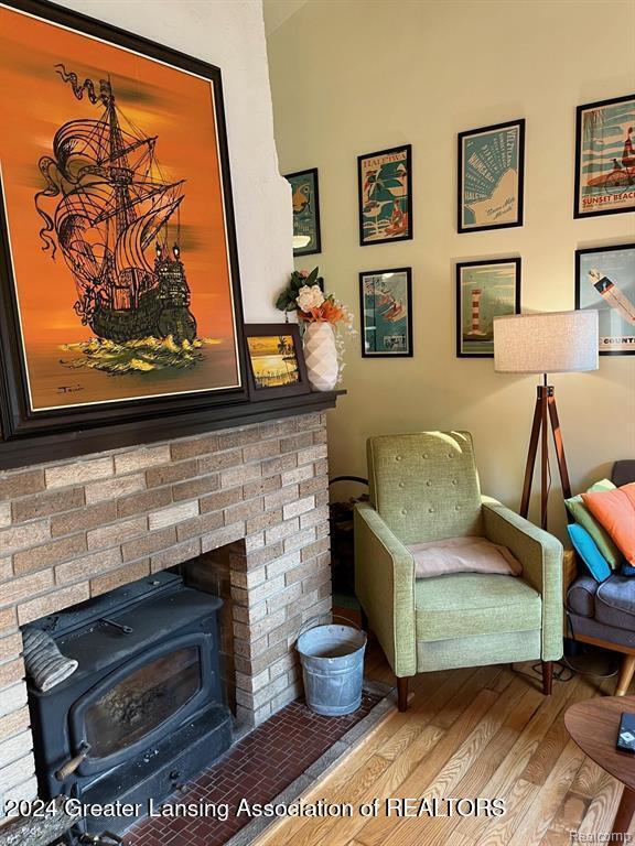 sitting room featuring a wood stove and wood-type flooring