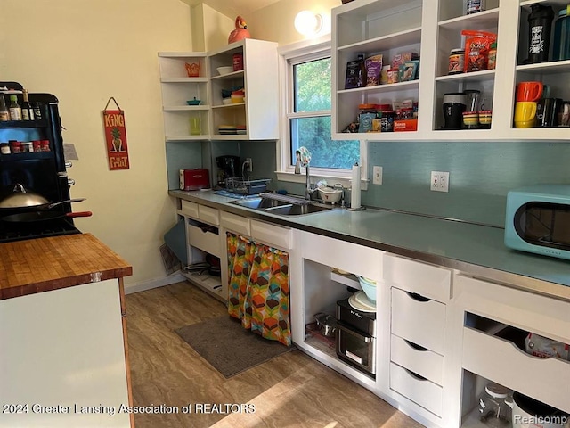 kitchen with wood counters, sink, white cabinets, and light wood-type flooring