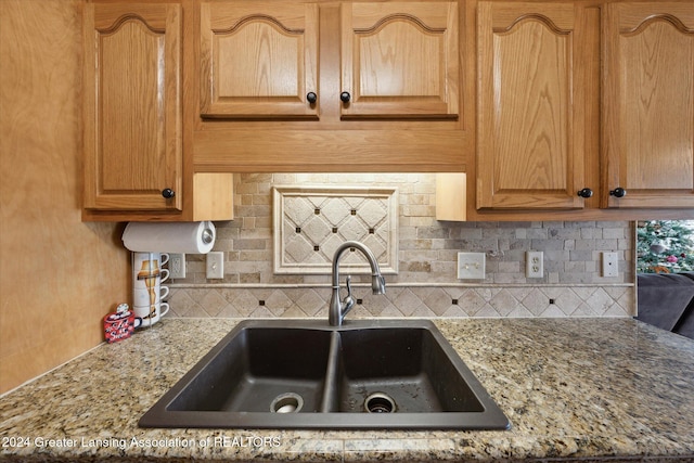 kitchen featuring sink, light stone counters, and backsplash