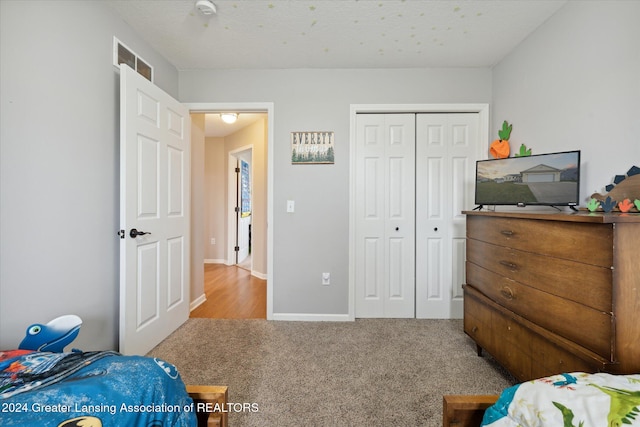 carpeted bedroom with a textured ceiling and a closet