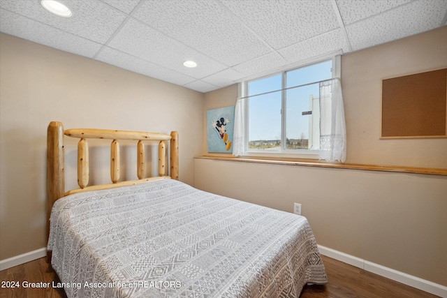 bedroom featuring a drop ceiling and dark wood-type flooring