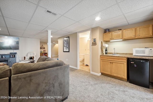 living room with a drop ceiling, light colored carpet, and wet bar