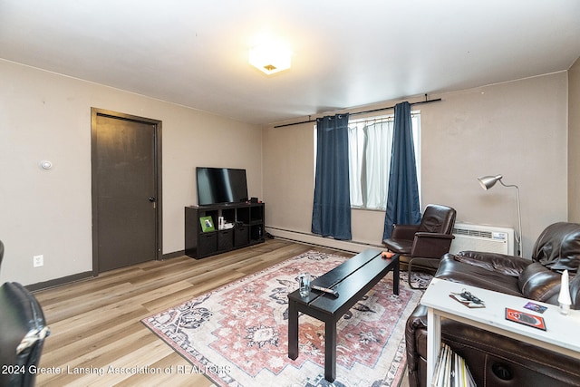 living room with baseboard heating, light hardwood / wood-style floors, and a wall mounted air conditioner