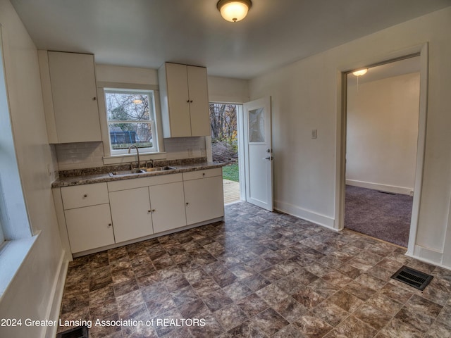 kitchen featuring white cabinets, backsplash, and dark stone counters