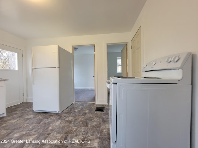 kitchen with white cabinets, white fridge, and washer / dryer