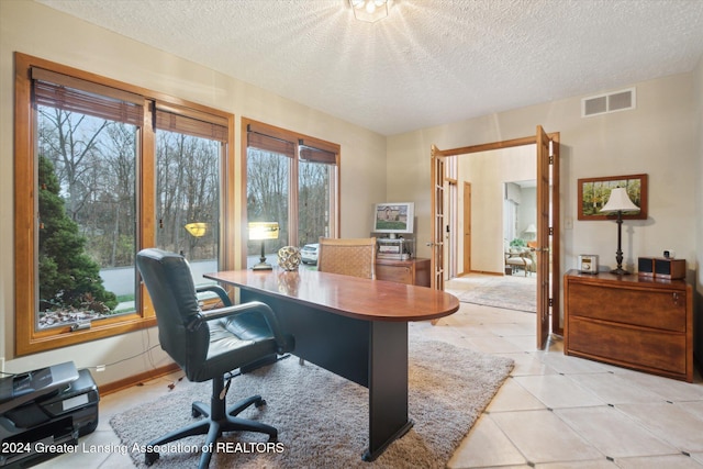 tiled office space with a textured ceiling, a wealth of natural light, and french doors