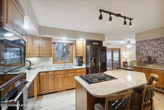 kitchen featuring plenty of natural light, a kitchen island, black appliances, and a textured ceiling