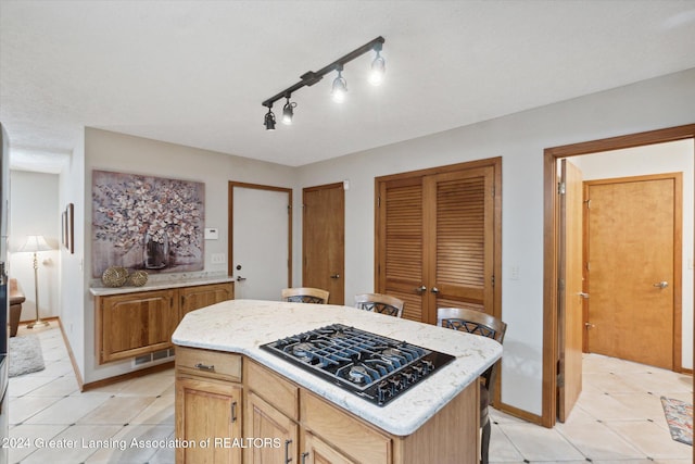 kitchen with a center island, gas stovetop, light tile patterned floors, and rail lighting