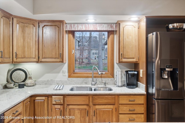 kitchen featuring stainless steel fridge, sink, and light stone countertops