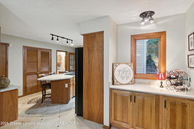 kitchen with light stone counters, kitchen peninsula, a textured ceiling, a breakfast bar, and light tile patterned floors