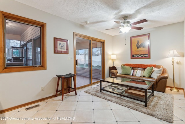 tiled living room with plenty of natural light, ceiling fan, and a textured ceiling