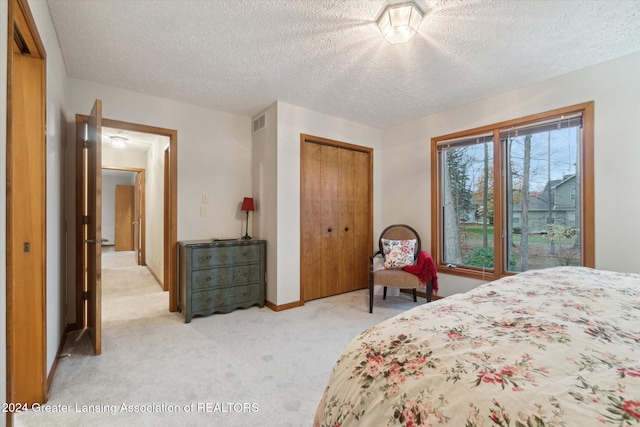 bedroom featuring a textured ceiling and light carpet