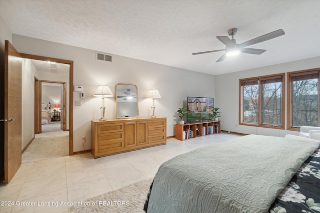 tiled bedroom featuring ceiling fan and a textured ceiling