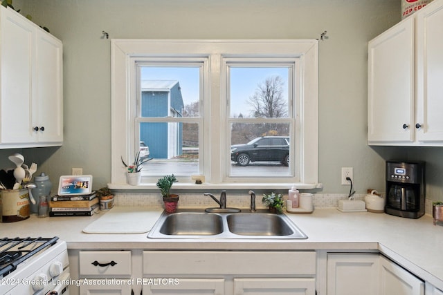 kitchen with white cabinetry, sink, and white range with gas stovetop