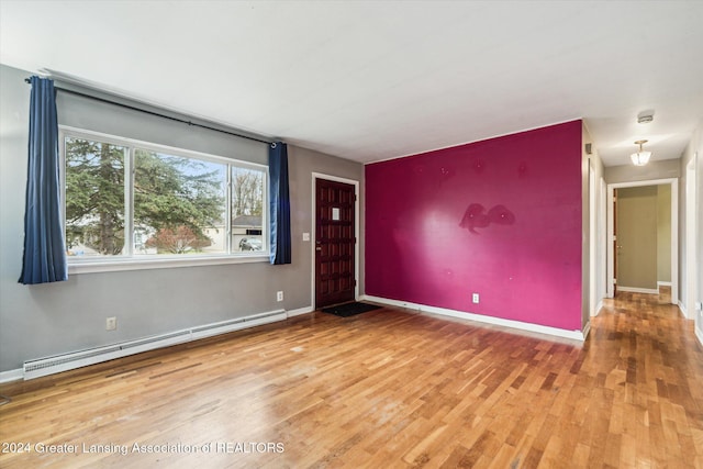 empty room featuring hardwood / wood-style floors and a baseboard heating unit