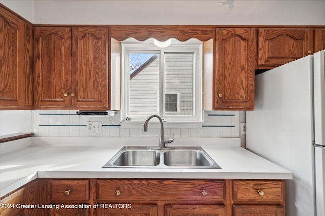 kitchen featuring backsplash, sink, and fridge