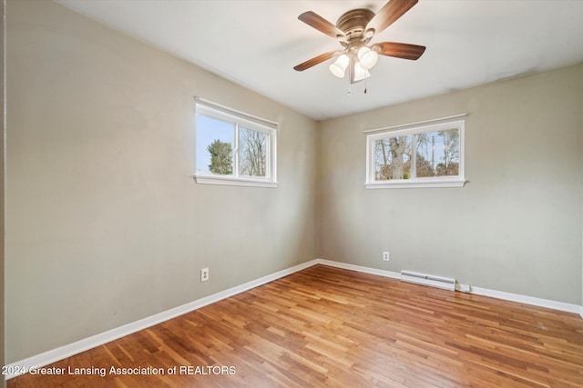 empty room with baseboard heating, ceiling fan, a healthy amount of sunlight, and light hardwood / wood-style floors