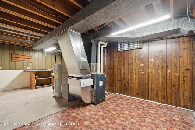 basement with heating unit, wood walls, and water heater