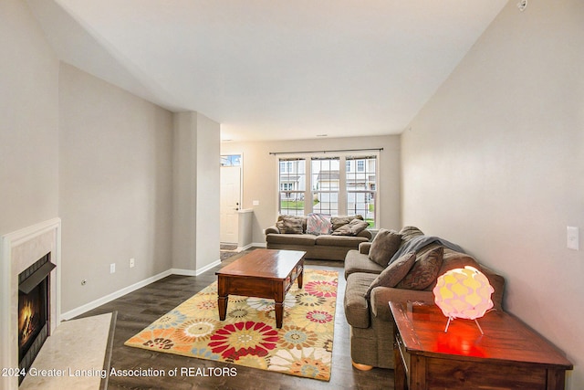 living room with a fireplace and dark wood-type flooring