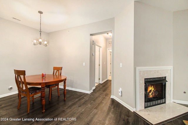 dining space featuring dark hardwood / wood-style floors, a high end fireplace, and an inviting chandelier