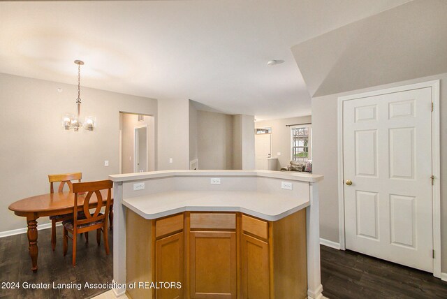 kitchen with a chandelier, pendant lighting, a kitchen island, and dark wood-type flooring