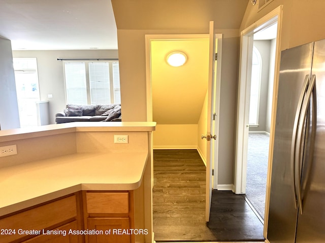 kitchen featuring stainless steel refrigerator, dark hardwood / wood-style flooring, and vaulted ceiling