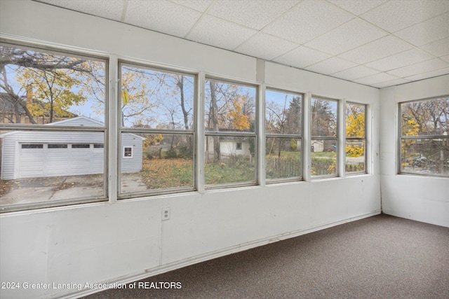 unfurnished sunroom featuring a drop ceiling and a healthy amount of sunlight